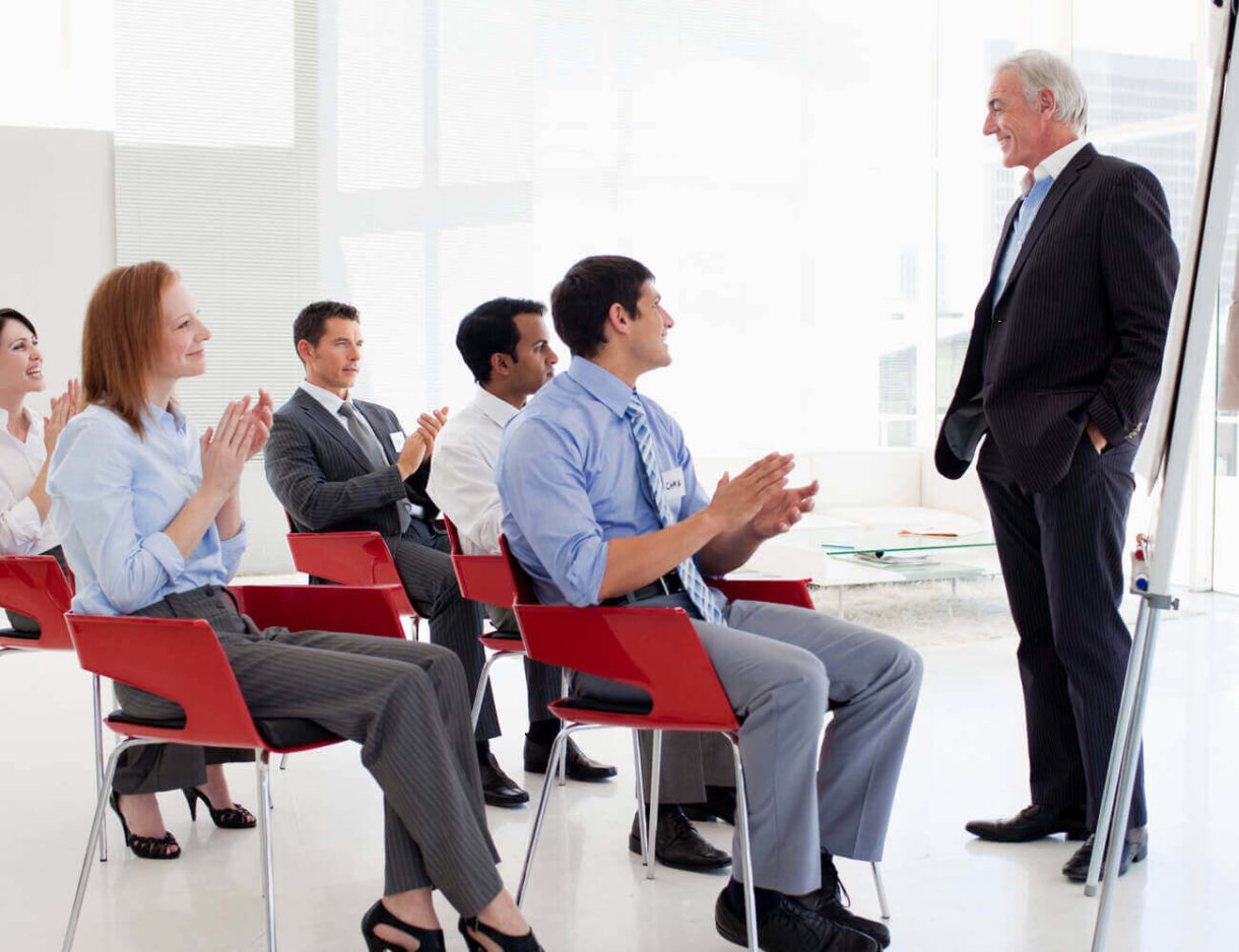 A diverse group of professionals applauding enthusiastically at a business conference.